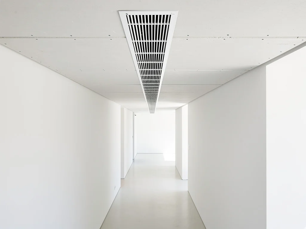 Bouche de diffusion encastrée au plafond d'un couloir, réseau gainable invisible